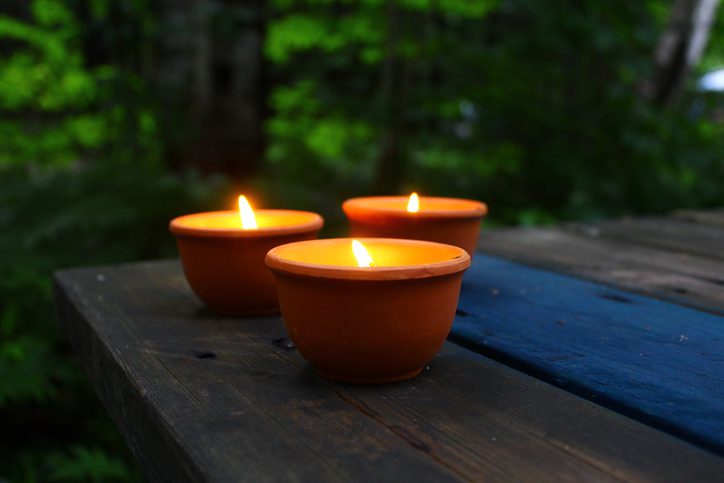 Citronella candles sit on a picnic table at dusk