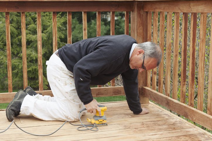 Man sanding the floor of a deck