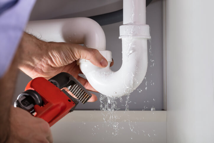 fixing leaky pipe with wrench