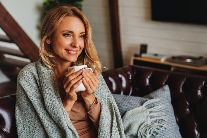 Woman snuggling with a blanket and a mug