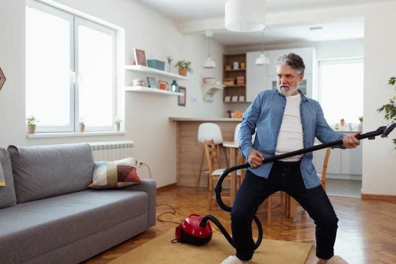 man playing air guitar on a vacuum in fuzzy slippers