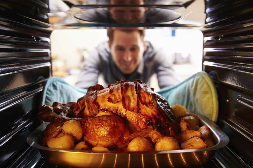 Man pulling a turkey out of the oven