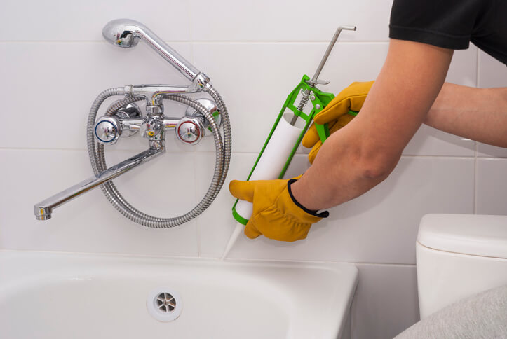 Person caulking a shower tub