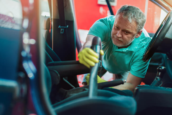 Man vacuums out a car interior