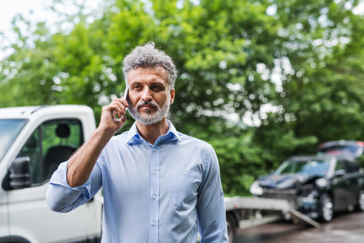 Someone on the phone in front of a tow truck