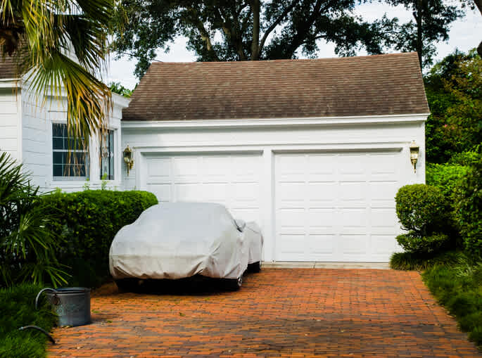 A car in a driveway under a cover