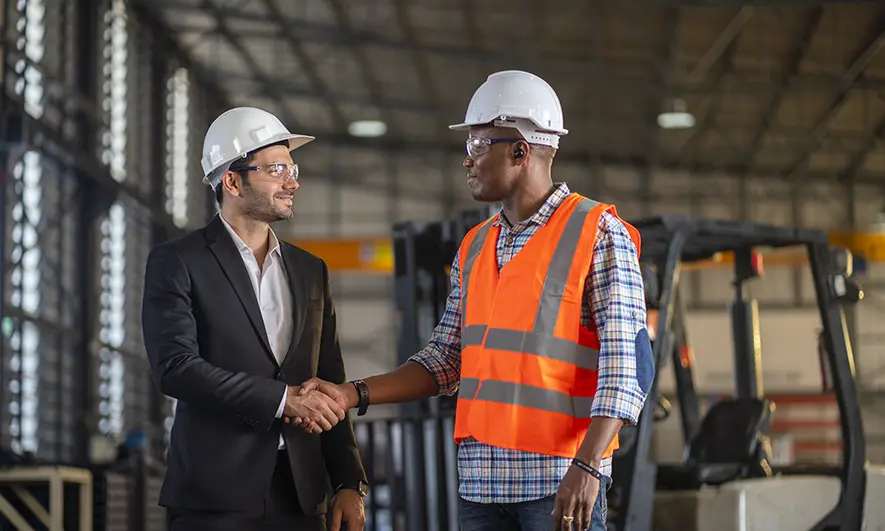 A person in a suit shaking hands with someone in a reflective vest