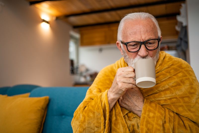 man in a blanket drinking a warm beverage