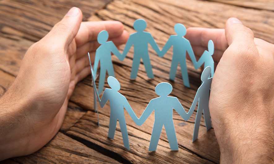 Hands encircling paper cutouts of people