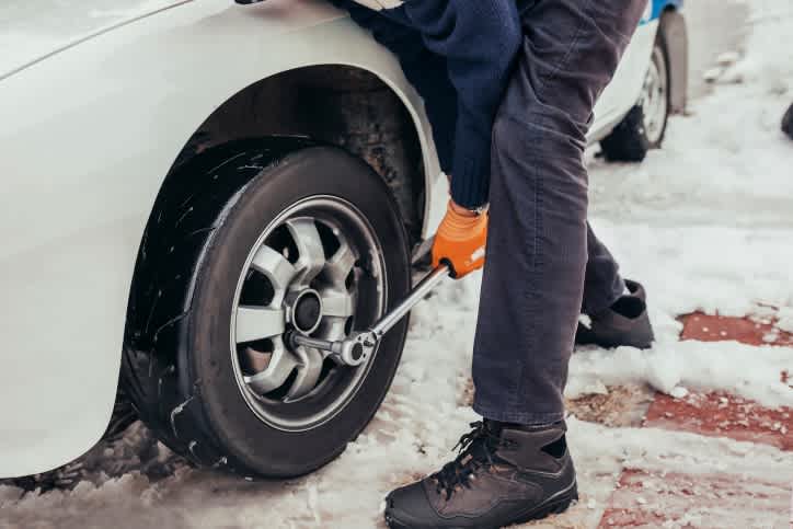 A person standing next to a car in the snow