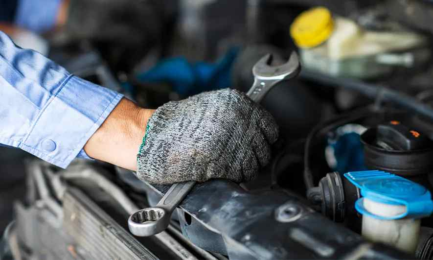 A mechanic works on a car with a wrench