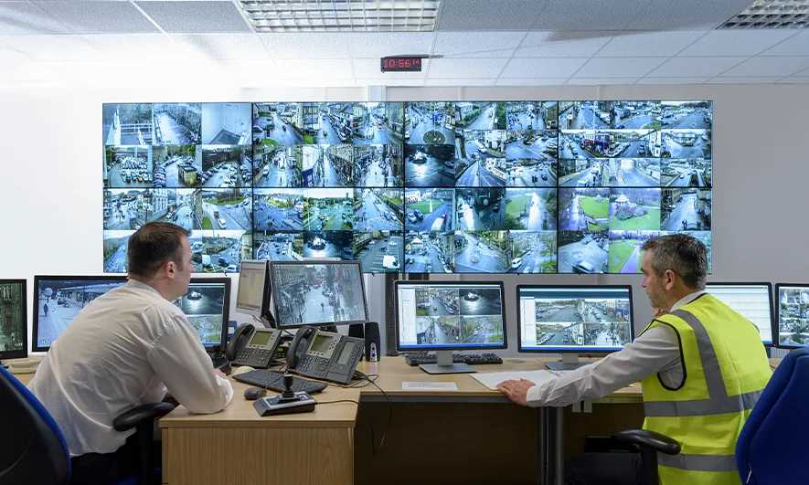Two security guards watching video monitors