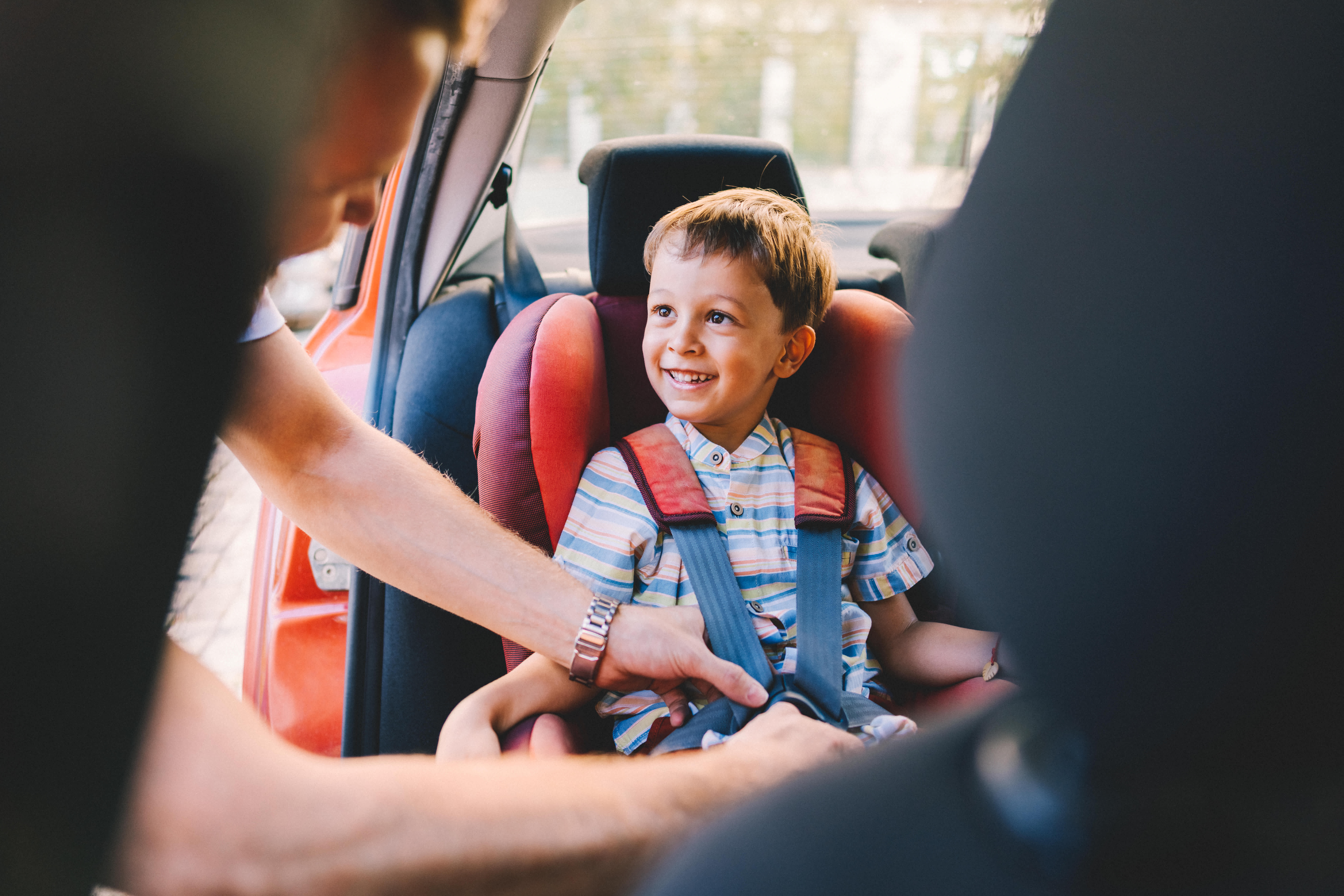 Parent buckling a child into a car seat