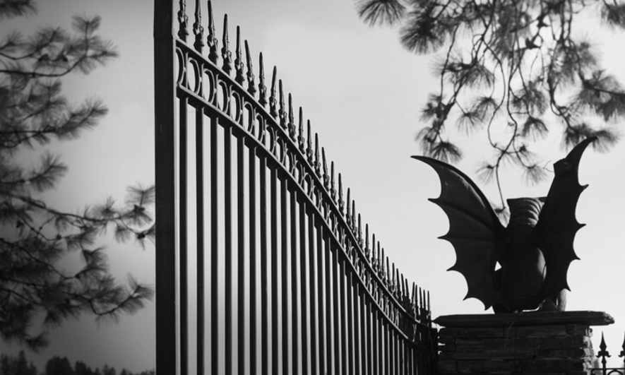 A gargoyle guarding an iron gate