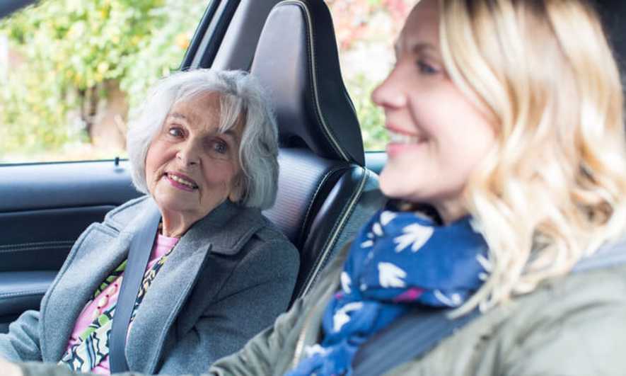 A grown woman drives her mom in a car