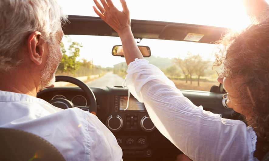 A middle-aged couple driving a convertible