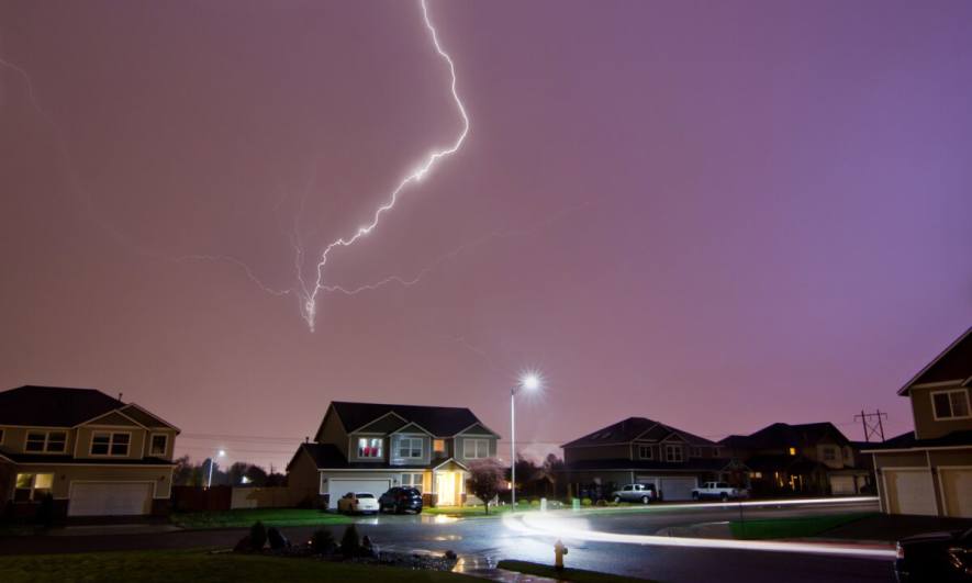 A lightning strike behind suburban homes