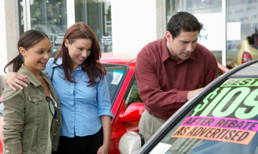 Parents shop for cars with their daughter