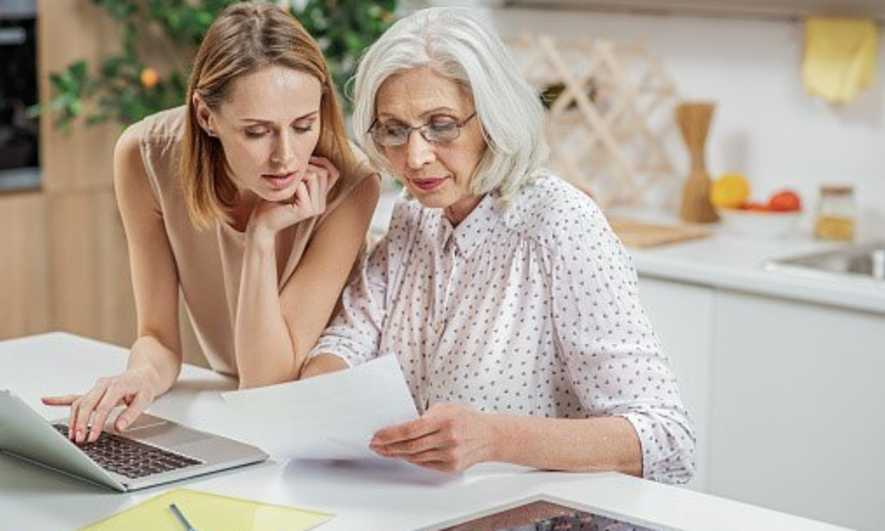 An adult woman sits with her mother, reviewing paperwork