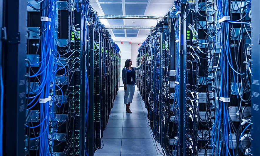 A women walking down an aisle at a data center warehouse