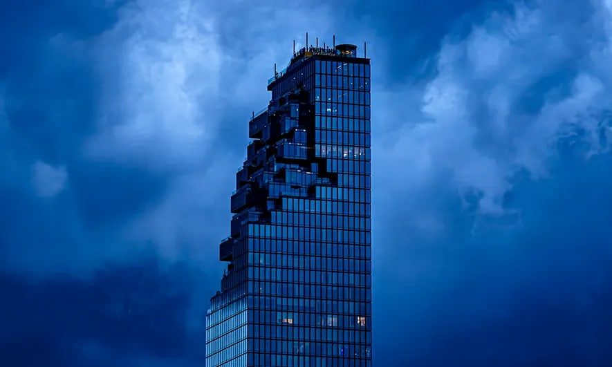 The top of a beige building with storm clouds behind it