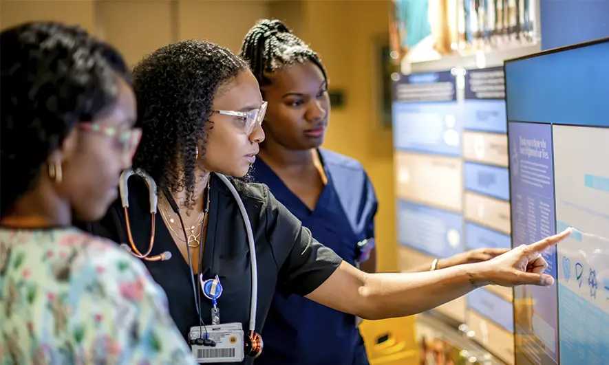 Healthcare professionals reviewing patient data on a touchscreen display.