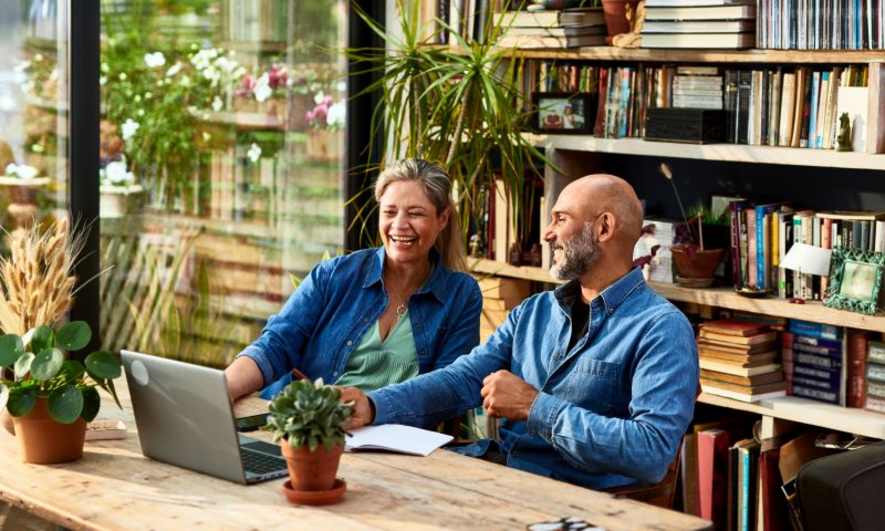 A couple sits together in front of a laptop