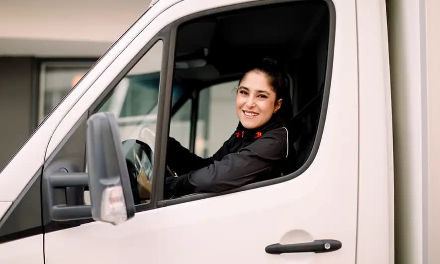 Person sitting in the driver’s seat of a commercial delivery van