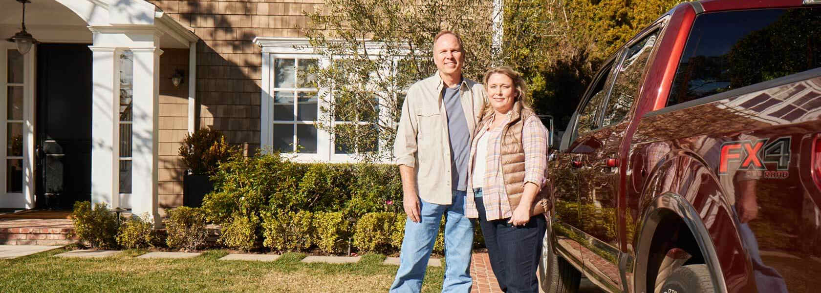 couple in front yard enjoying savings from homeowners insurance discounts