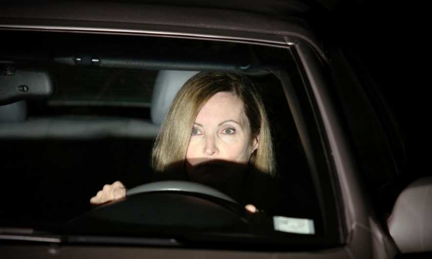 A woman driving with a bright, harsh light in her face