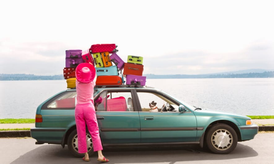 Colorful suitcases tied to the top of an old station wagon
