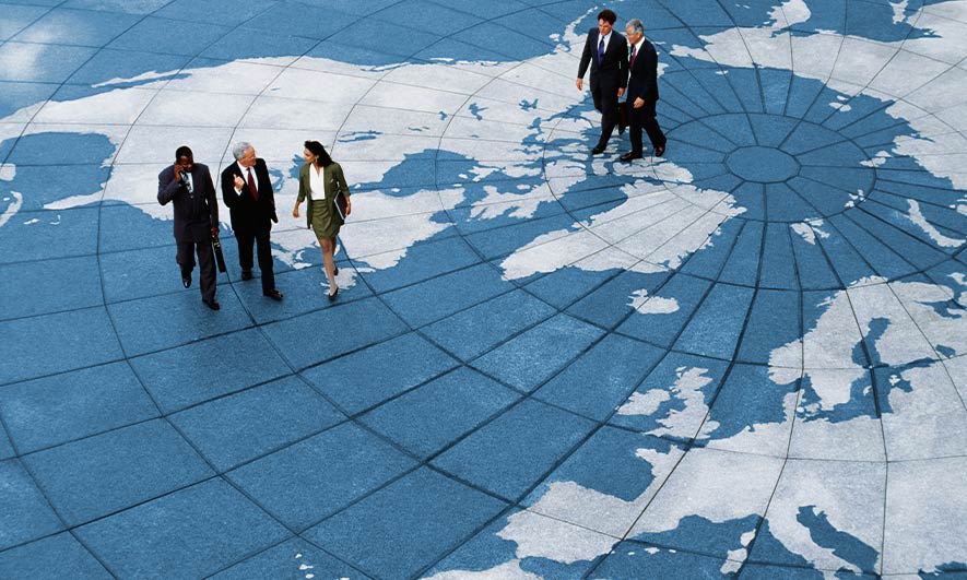 Business professionals walking on a sun dial in the shape of a globe.