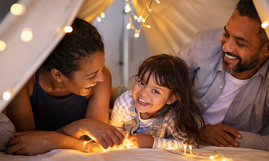 happy parents and child playing in tent