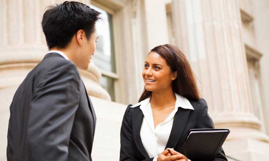 man and woman talking in front of large building