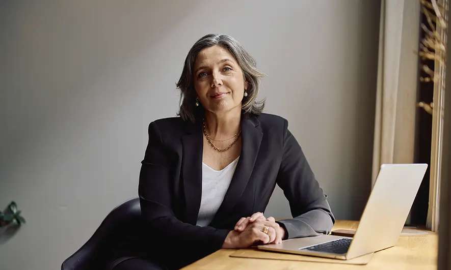 Smiling business woman sits with a laptop on her desk