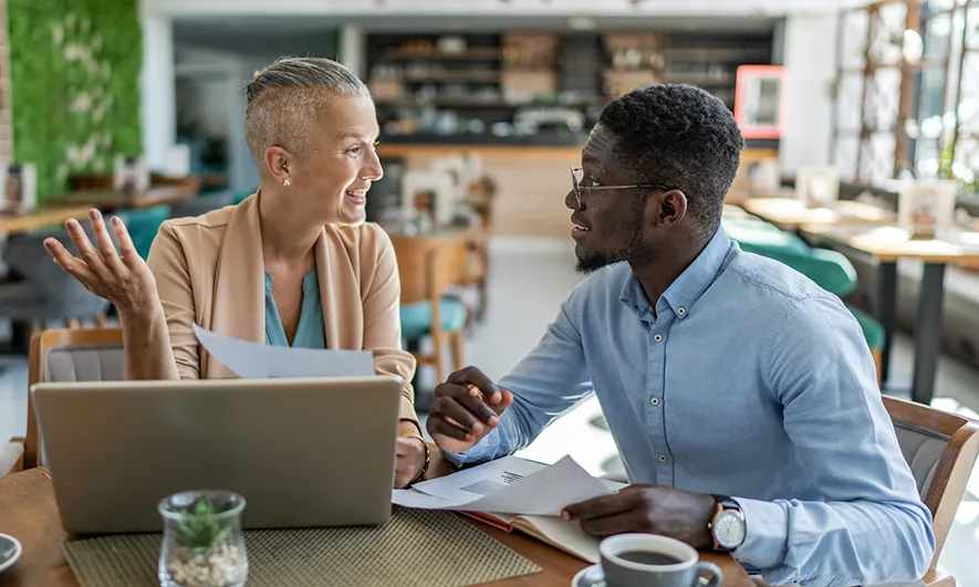 Two professionals chatting at their computers
