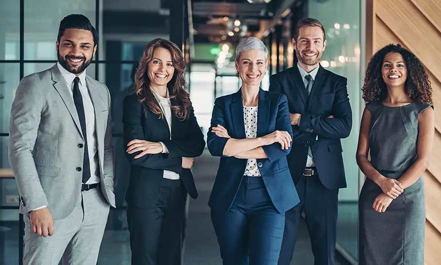 A group of professionals standing in a hallway facing the camera smiling.