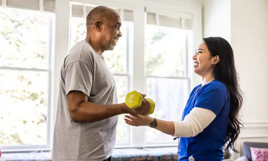 Home health worker assists an elderly man in exercises
