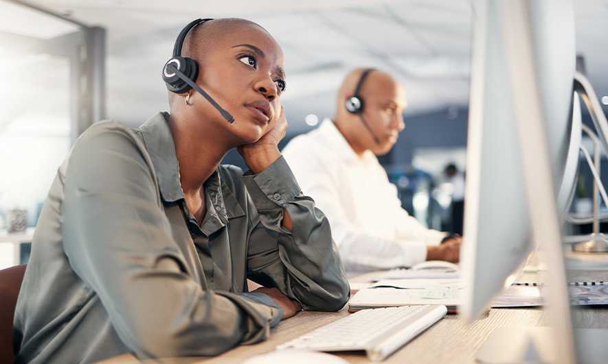 Stressed call center employee looking anxious while working at her computer.