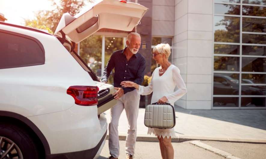 A couple getting travel bags out of a car
