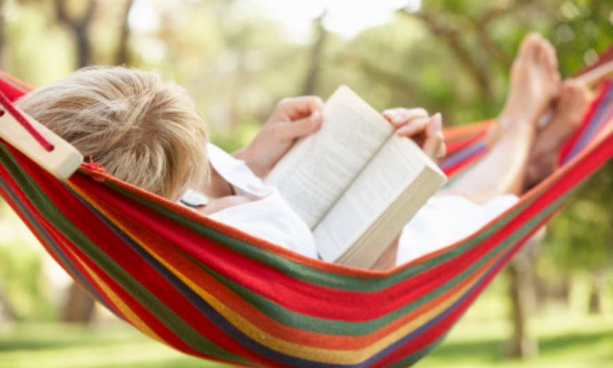 Woman Relaxing In Hammock With Book