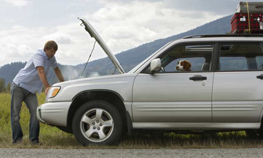 A man examines his broken down car