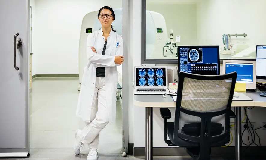 Radiologist stands near a large medical scanner