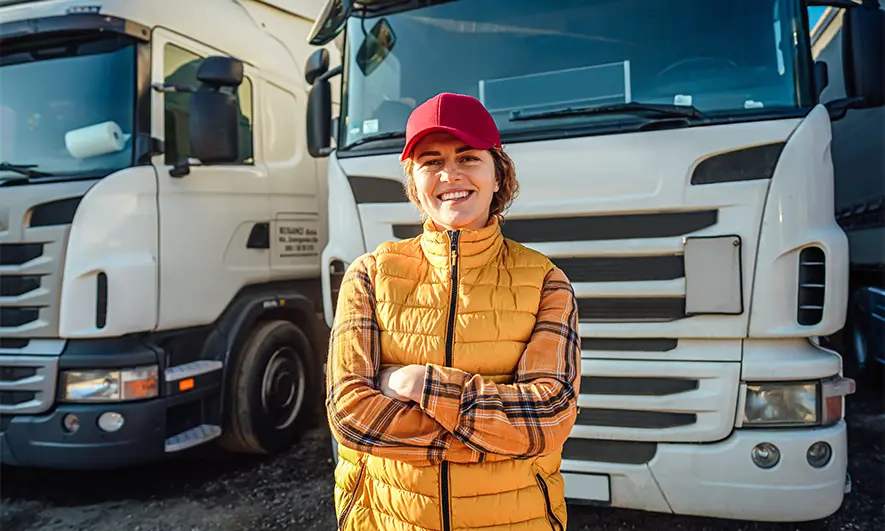 A truck driver standing in front of her rig