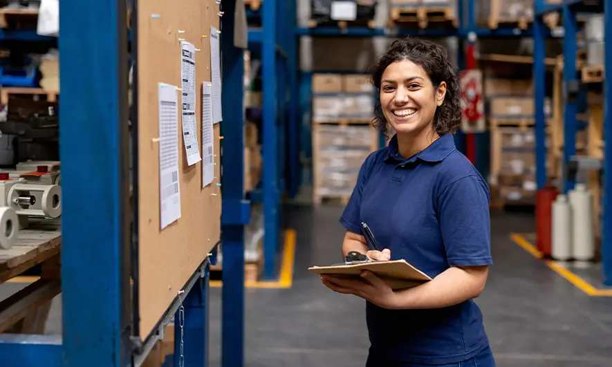 A warehouse worker consulting their board